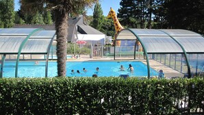 Un espace piscine agrémenté d’une statue de girafe, entouré de verdure et doté de structures abritées.