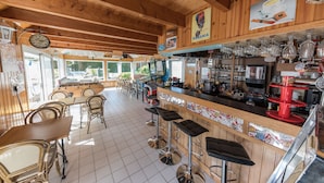 Een rustieke bar met houten meubels, een toog met krukken en diverse baraccessoires.