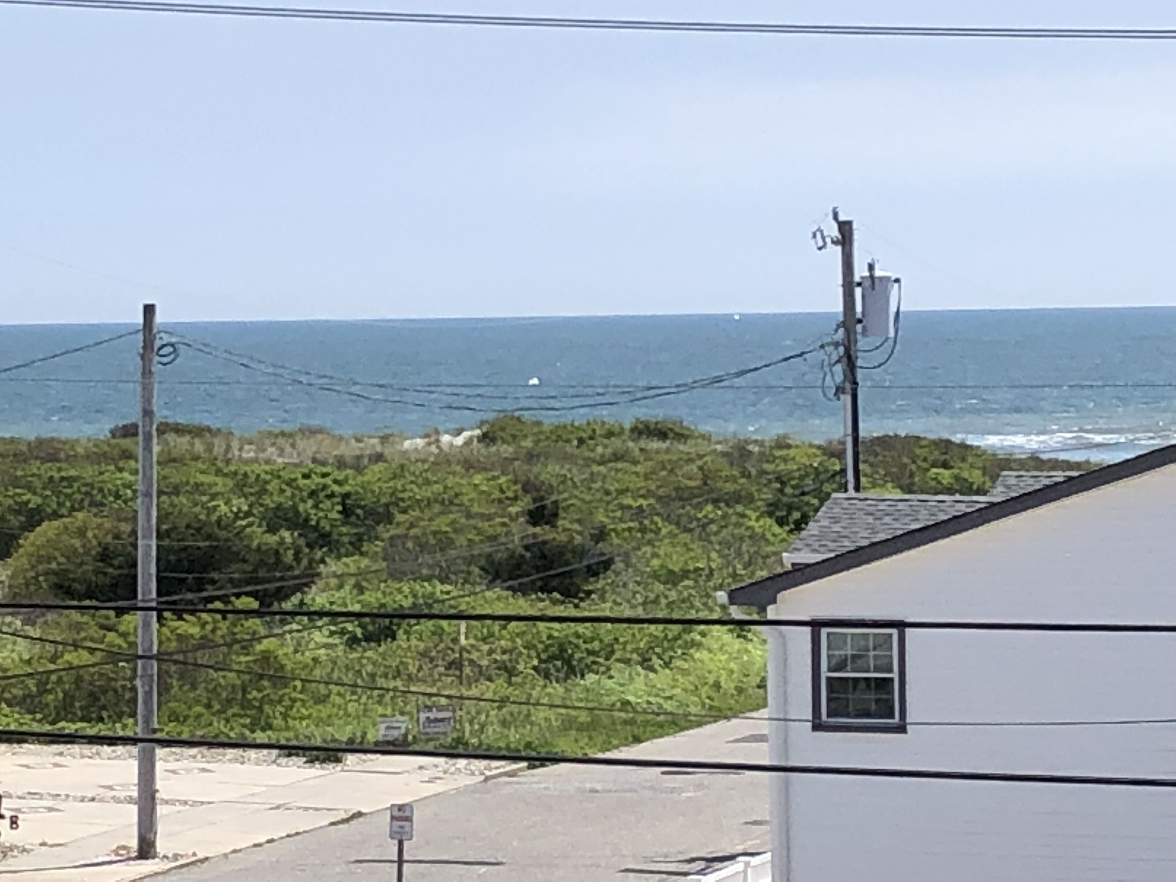 A coastal view with a white building, power lines, and a clear sky.