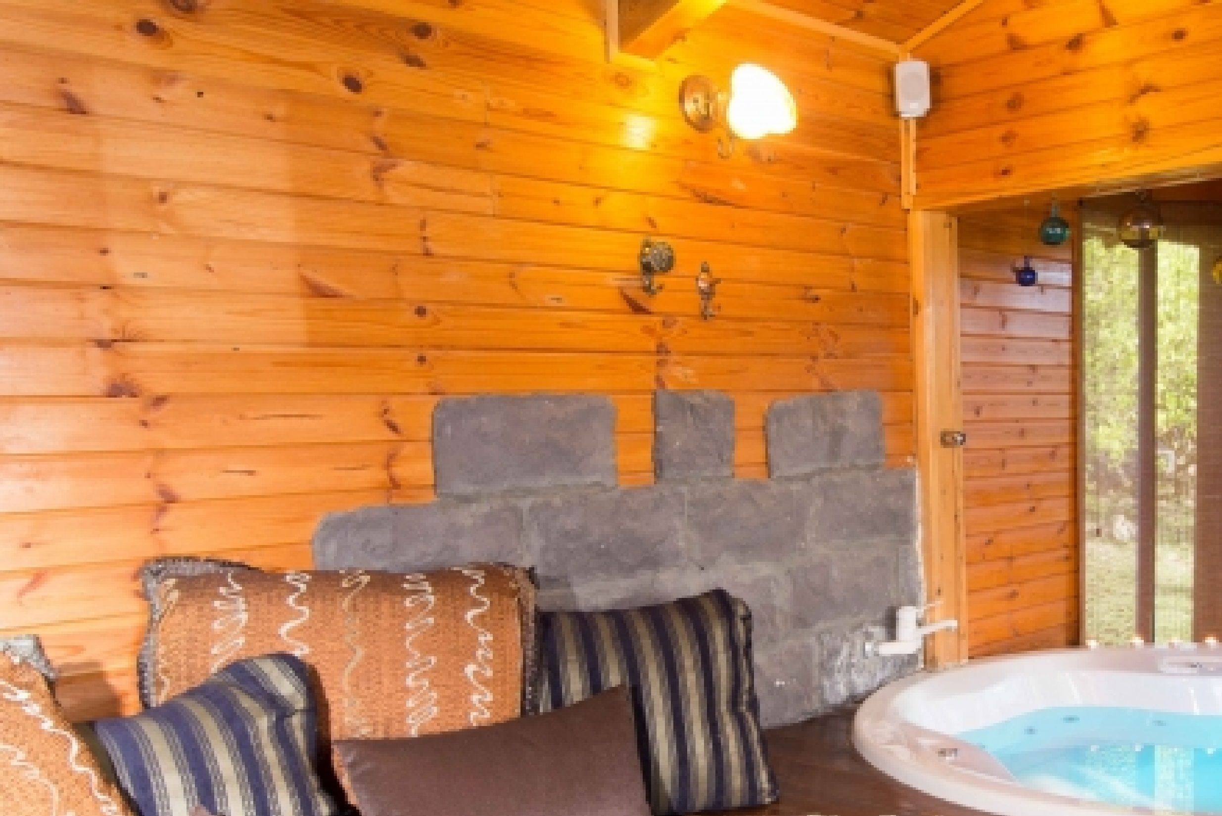 Ein Blockhaus-Interieur mit Kamin aus Naturstein, Holzboden und Whirlpool.
