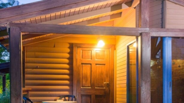 A log cabin with a wooden exterior, a front door, and a small porch area. - Indigolan (Ma'ale Gamla)
