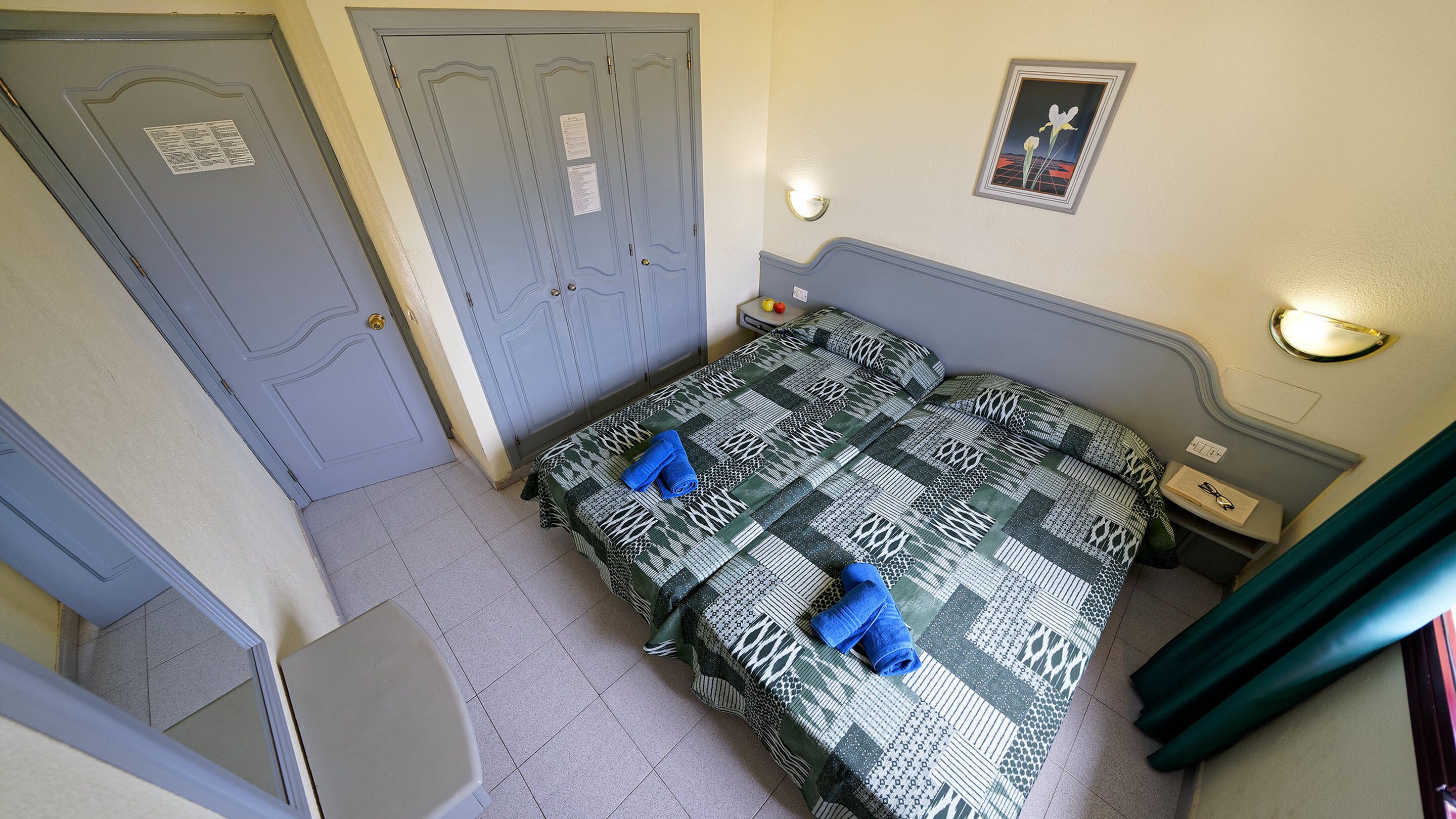 Un dormitorio con una cama, una mesita de noche, un escritorio y una puerta.