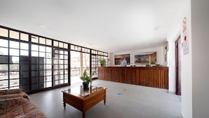 Un hall d’entrée spacieux avec un comptoir de réception, un canapé à motifs et une table basse agrémentée d’une plante.