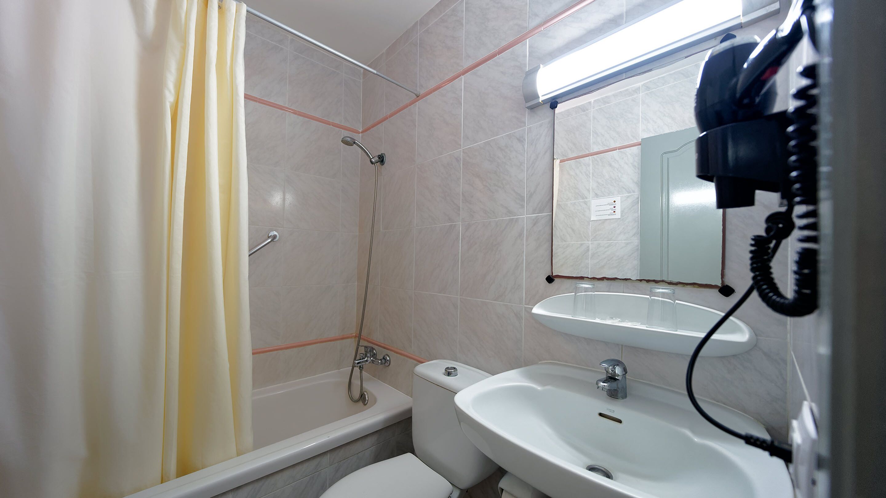 A bathroom with a shower, toilet, sink, and a mirror.