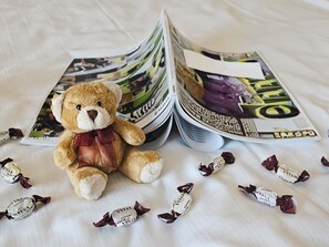 A teddy bear on a bed with magazines and chocolates. - Arvena Park Das Hotel am Franken-Center (Nuremberg)
