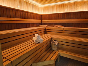 Una sauna con bancos de madera, toallas y un cubo.