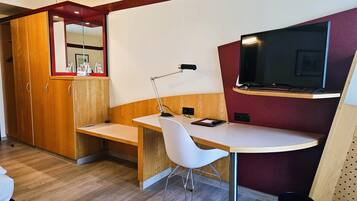 Una habitación compacta con escritorio, silla y televisor fijado a la pared.