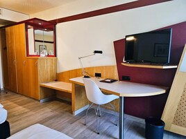 Una habitación compacta con escritorio, silla y televisor fijado a la pared.