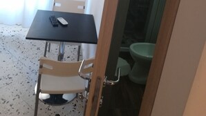 Une petite pièce comprenant une table, des chaises, des toilettes et un espace douche.