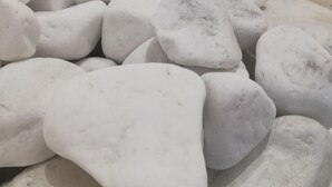 Une rangée de pierres blanches, de formes irrégulières, disposées en ligne le long d’un mur.