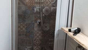 Eine Dusche mit gemusterten Fliesen und einer Handbrause.