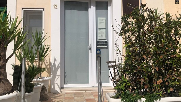 A building entrance with a glass door, numbered 12, and a parking meter. - Recinto Antico Sweet Rooms (Matera)