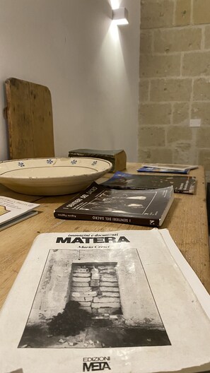 A table with books, a bowl, and a magazine. - Recinto Antico Sweet Rooms (Matera)