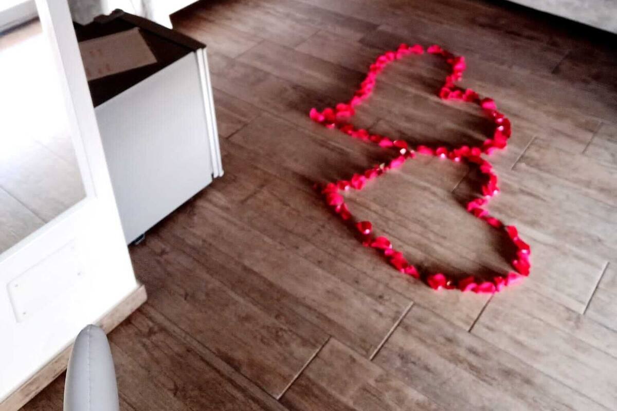 Un dormitorio con una cama, un sofá y una decoración en forma de corazón en el suelo.