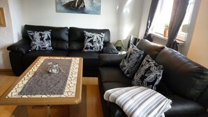 Una sala de estar moderna con un sofá de cuero negro, una mesa de centro de madera y un cuadro en la pared.