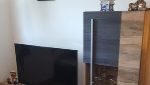 Una sala moderna con televisor de pantalla plana, mueble de madera y elementos decorativos.
