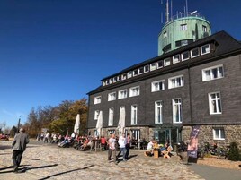 Um edifício com fachada de pedra, várias janelas e uma torre verde com antenas.