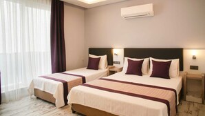A hotel room with two beds, each with a headboard, bedside tables, and a wall-mounted air conditioner. - Af-Ra Hotel (Konyaalti)