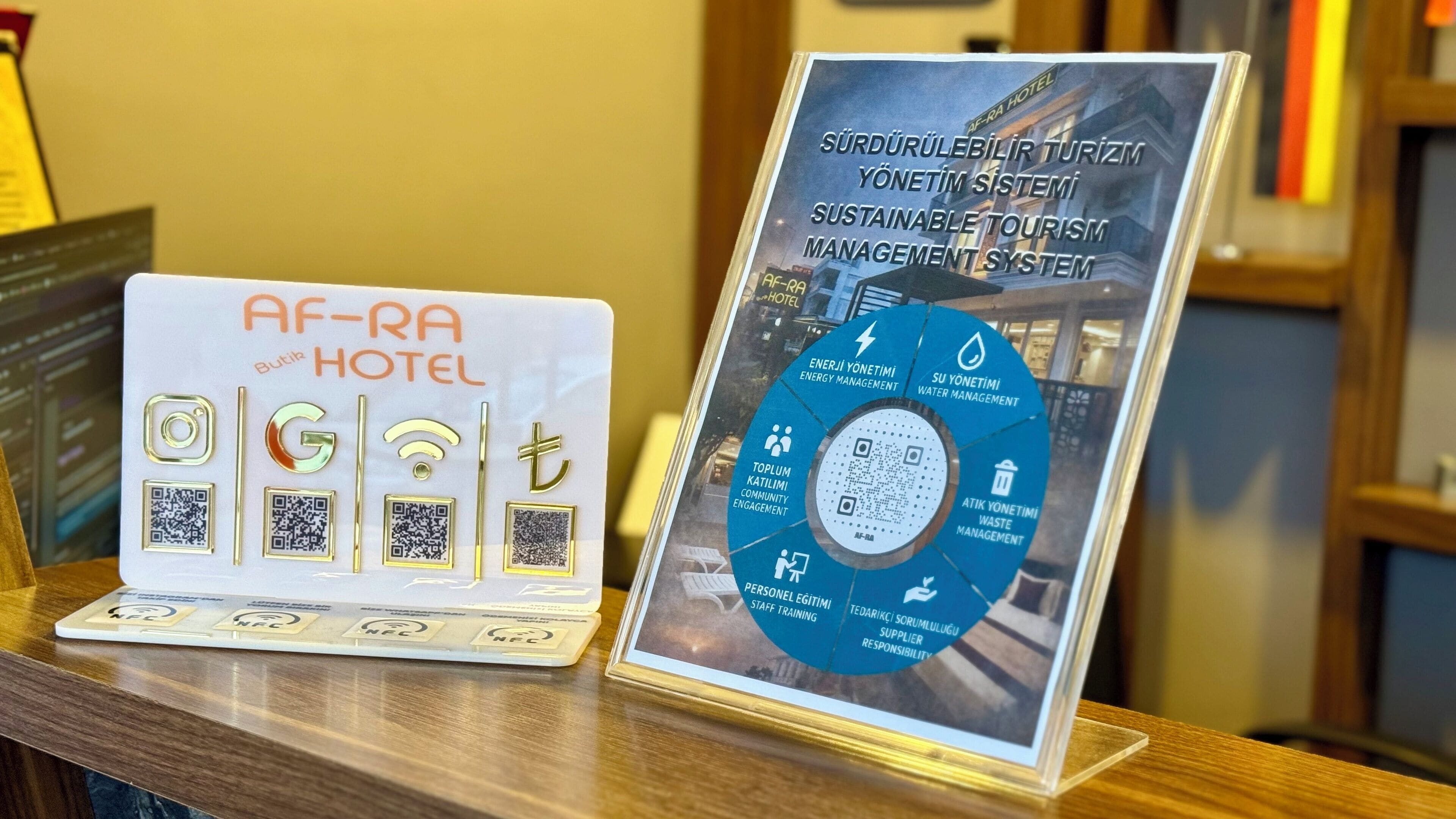 Un panneau d’affichage présentant un schéma circulaire intitulé « Système de gestion du tourisme durable » et un ordinateur portable doté d’étiquettes NFC.