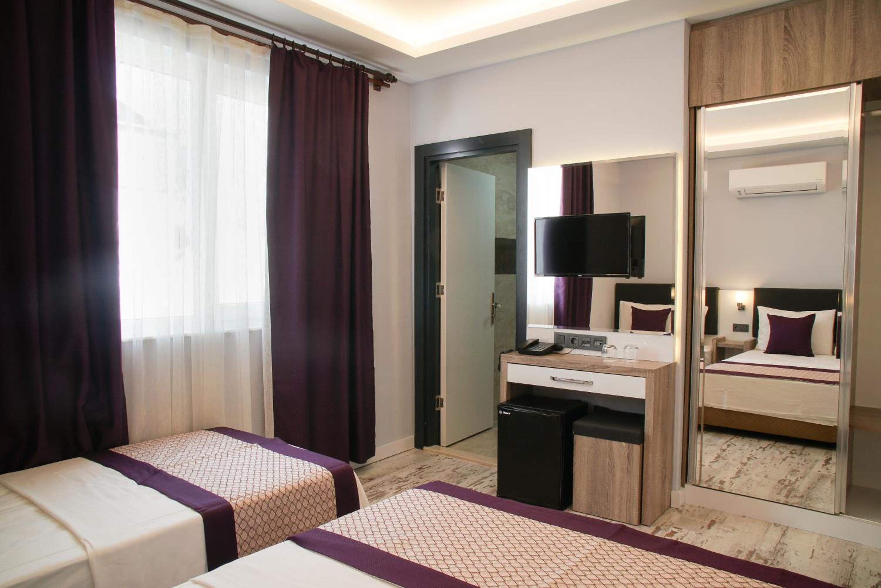 Habitació d'hotel amb dos llits, una taula de treball, un mirall i una televisió.