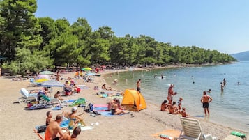 Ein Strand mit Personen, die sich sonnen und schwimmen, und einem aufgebauten Zelt.