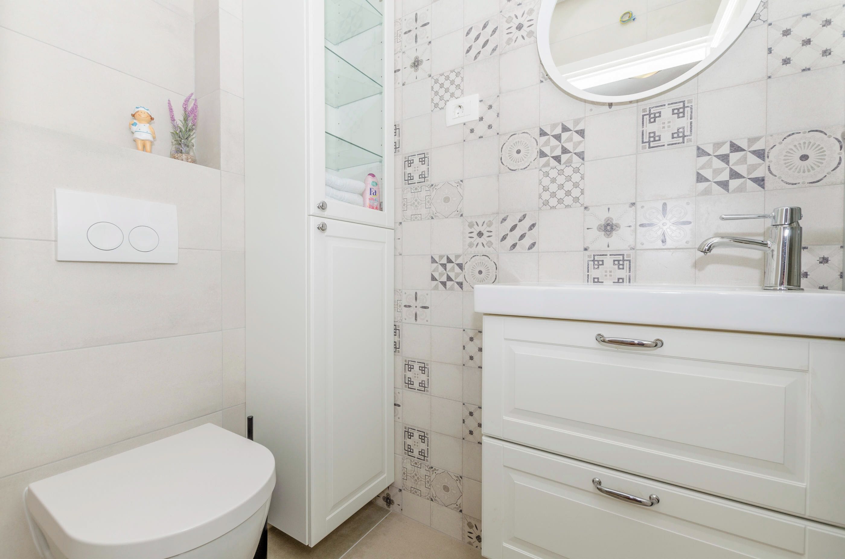 Ein Badezimmer mit Toilette, Waschbecken und Fliesen mit Muster.