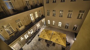 A multi-level hotel atrium with a central open area featuring outdoor seating under yellow umbrellas. - EA Hotel New Town (Prague)