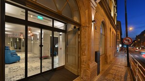 A hotel entrance with a glass door, a sign indicating an exit, and a no parking sign on the sidewalk. - EA Hotel New Town (Prague)