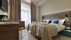 A hotel room with a large bed, a desk with a coffee maker, and a chair. - EA Hotel New Town (Prague)