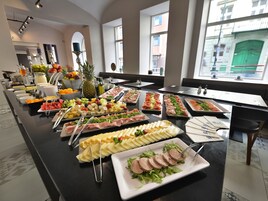 Buffet com diversos alimentos e vista da cidade por grandes janelas.