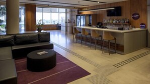 A modern bar area with a counter, stools, and a television. - Rio Hotel by Bourbon Campinas (Campinas)