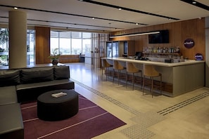 Eine moderne Bar mit einer Theke, Hockstühlen und einem Fernseher.