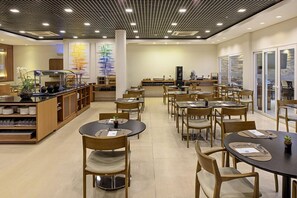 A modern restaurant with round tables and chairs, a central counter, and a decorative wall with vertical elements.