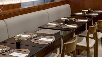 A restaurant with long tables, wooden chairs, and a cushioned bench.