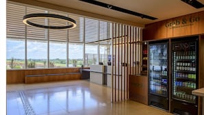 A modern interior with a reception desk, a 'Grab & Go' vending area, and large windows offering a view of greenery. - Rio Hotel by Bourbon Campinas (Campinas)