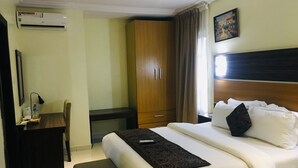 Ett hotellrum med en säng, ett skrivbord, en stol, en garderob och en luftkonditioneringsanläggning.