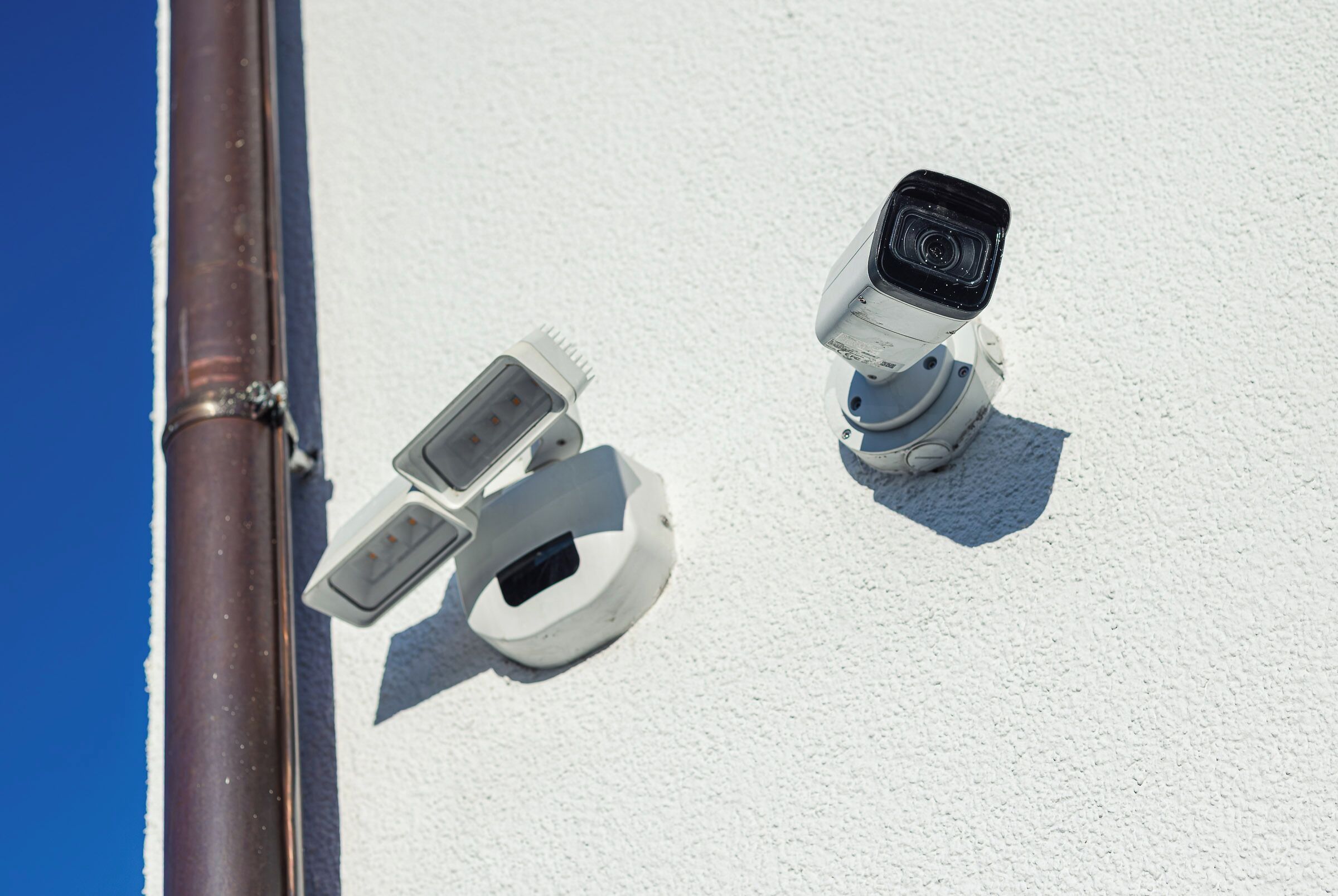 Two security cameras mounted on a white wall.