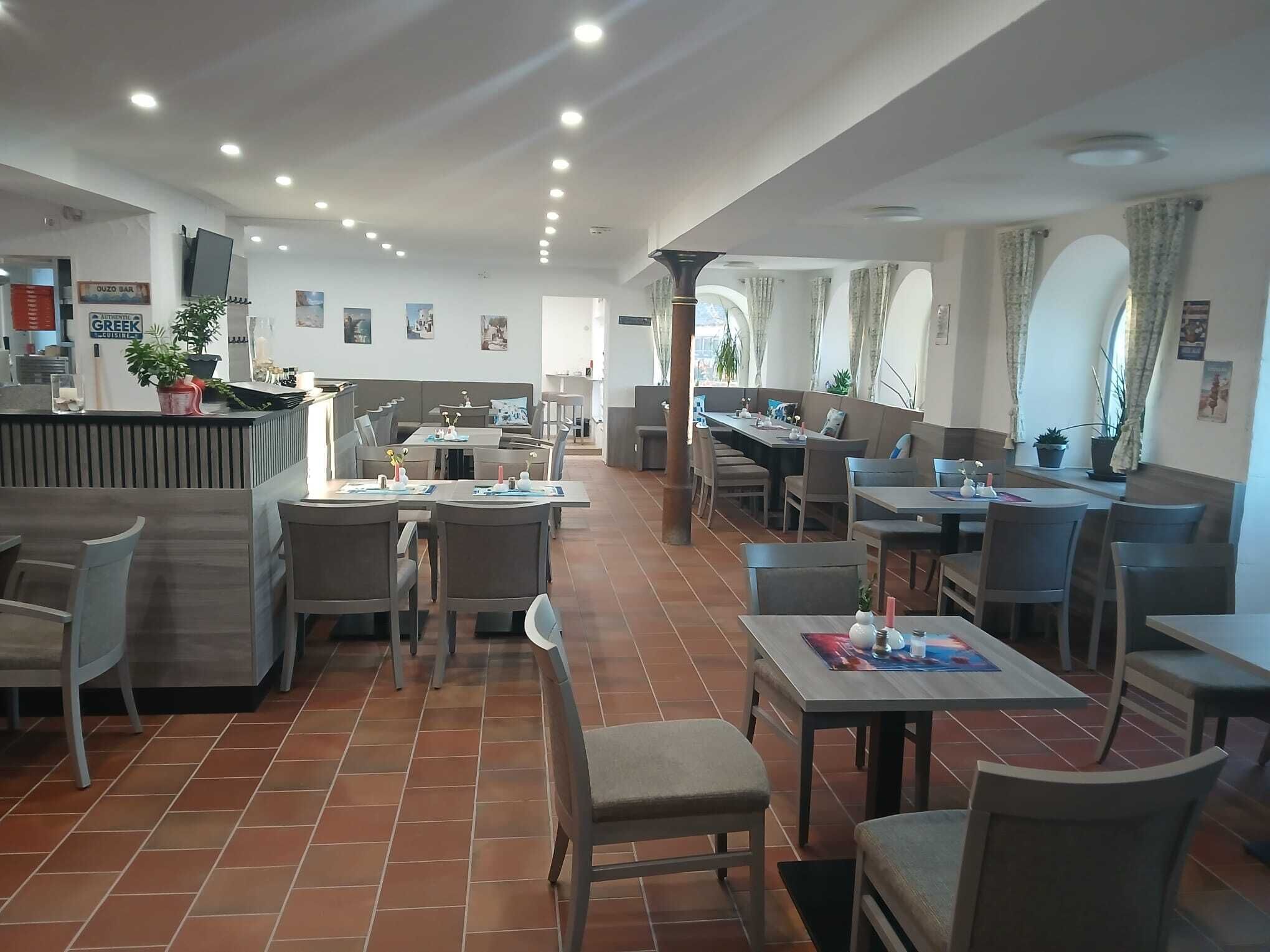 Ein Restaurant mit einer Theke, Sitzbereichen und einem Fliesenboden.