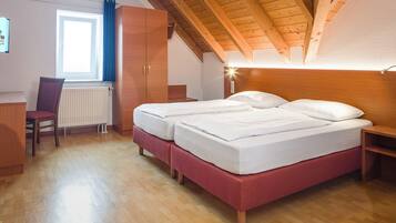 A bedroom with a wooden ceiling, two beds, a chair, a desk, and a window with curtains.