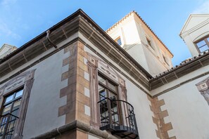 Um canto de um edifício com varanda, janela e fachada decorativa.