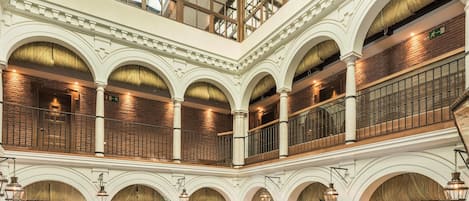 Un atrium à plusieurs niveaux, doté de plafonds en arc de cercle et d’un espace central ouvert.