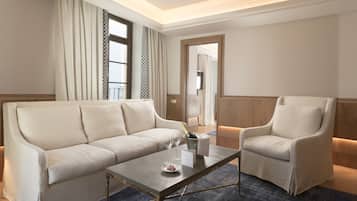 A hotel room with a sofa, armchair, and a small table with a bottle of champagne and glasses.