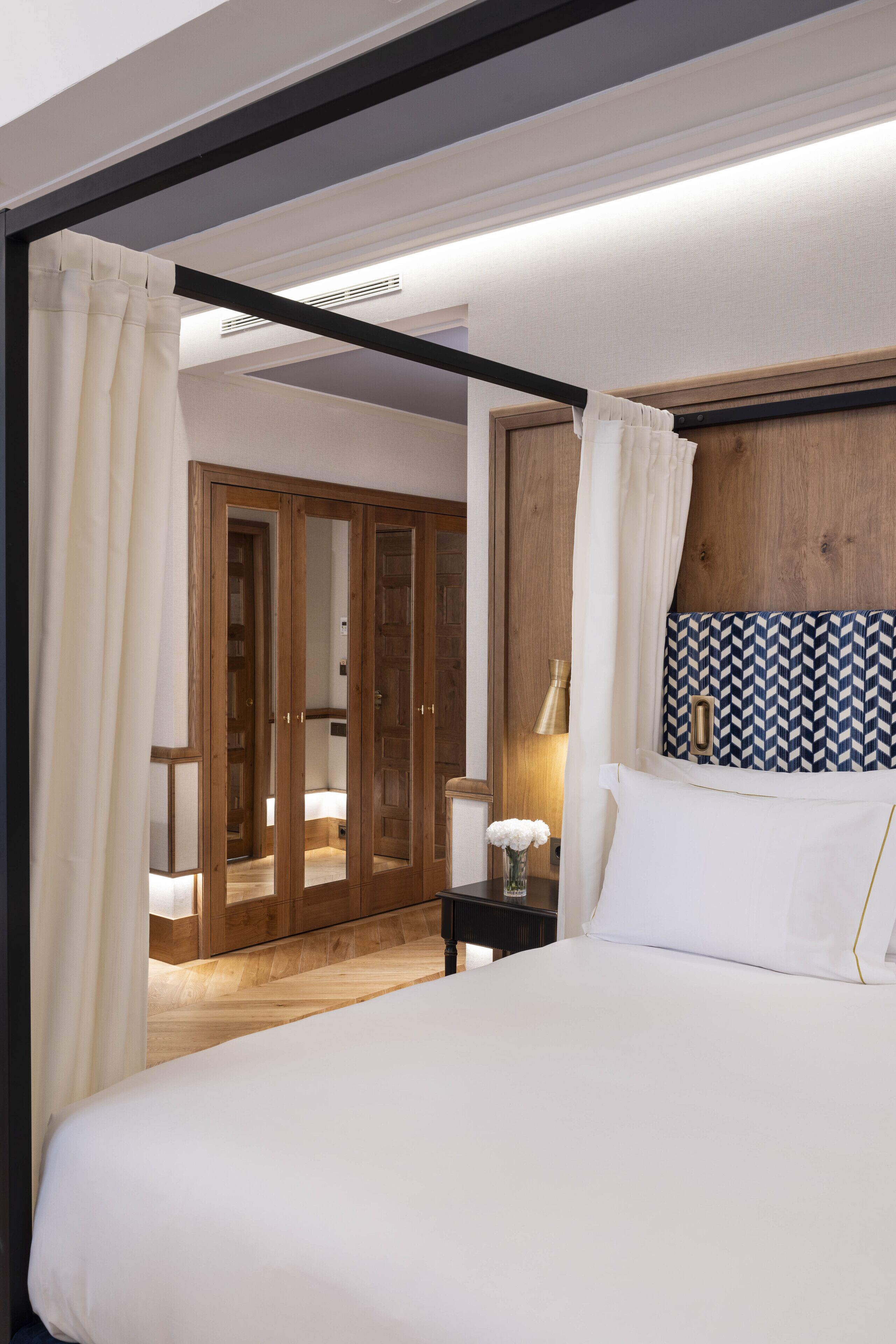Un dormitorio con una cama grande, un armario de madera y una mesita de noche con lámpara.