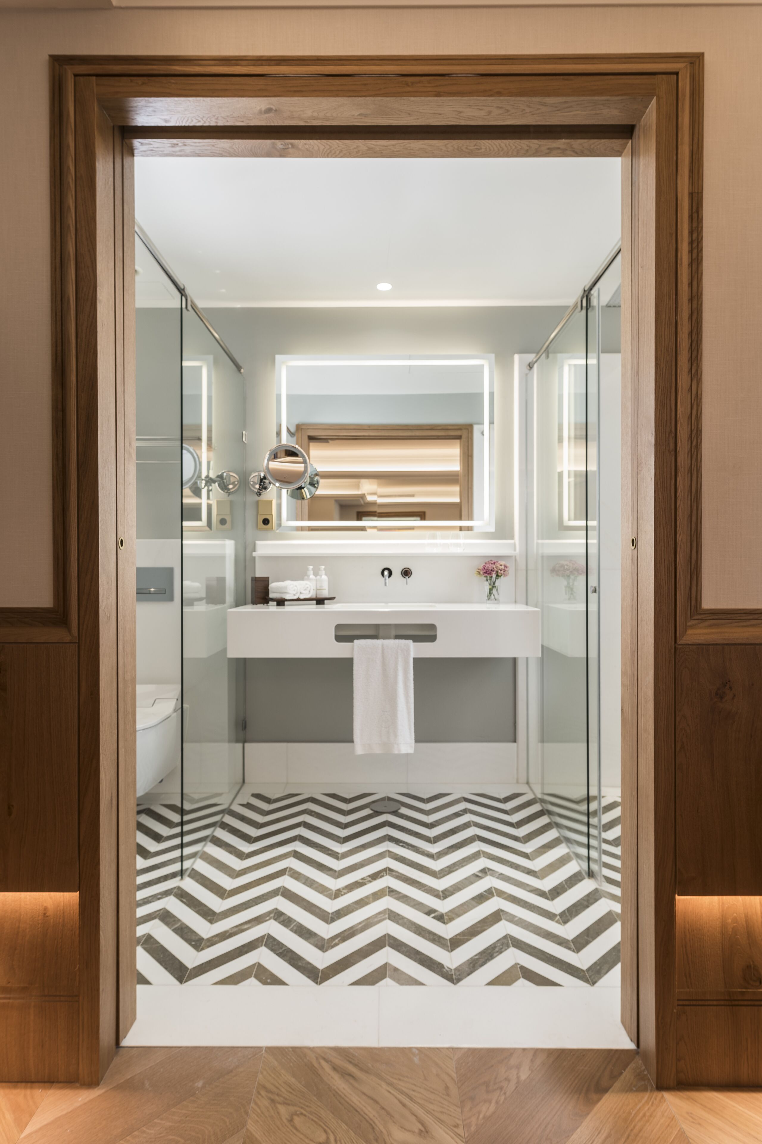 A modern bathroom with a glass shower enclosure, a white sink, and a mirror above it.