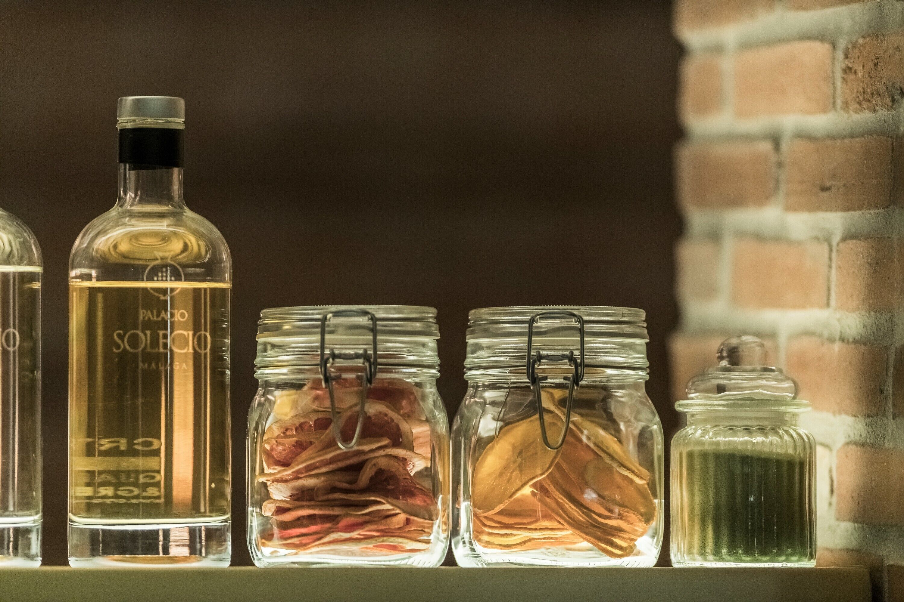 Una estantería con varios recipientes de vidrio, incluyendo una botella y frascos con cierres metálicos.