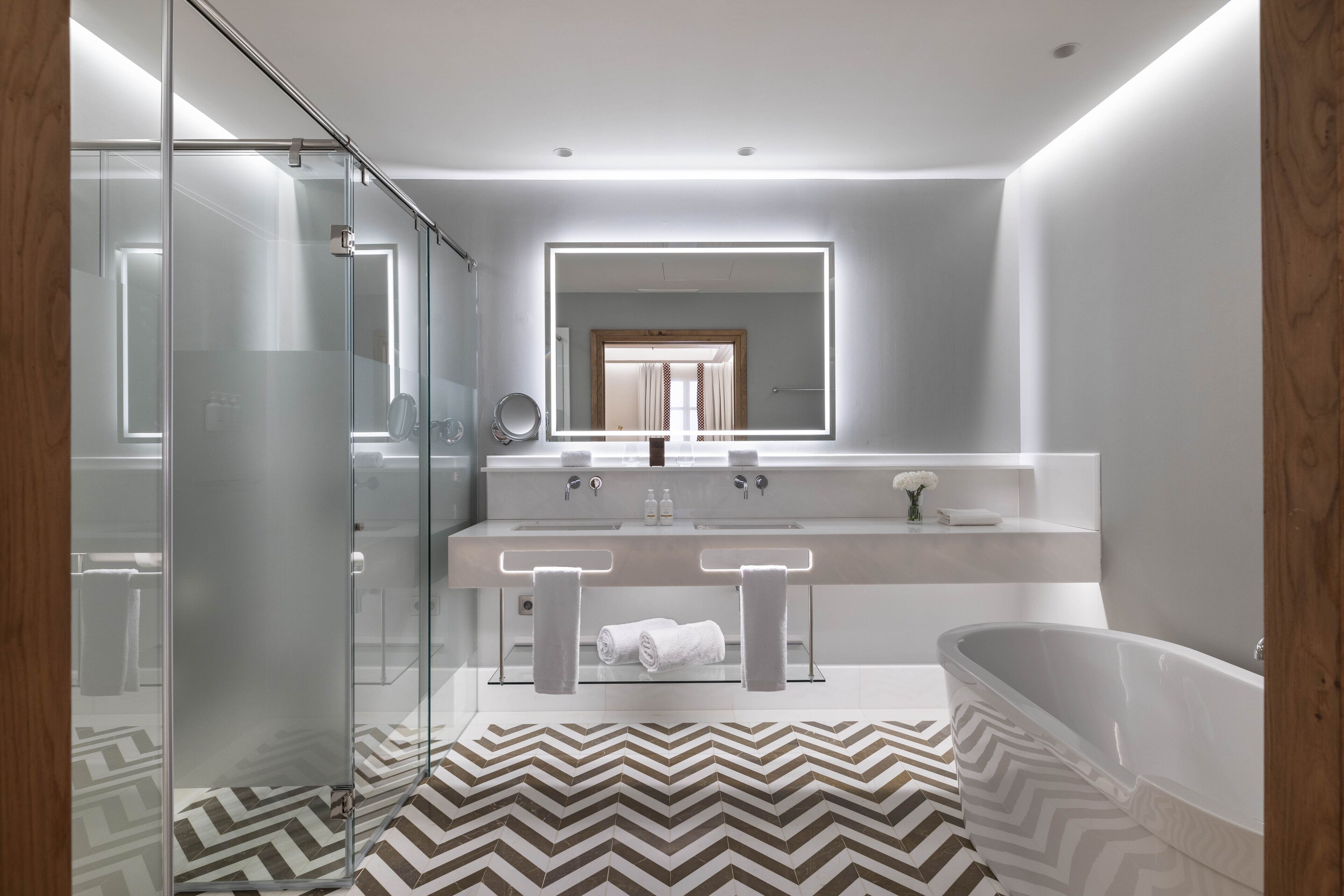 A modern bathroom with a glass shower enclosure, a freestanding bathtub, and a vanity with dual sinks.