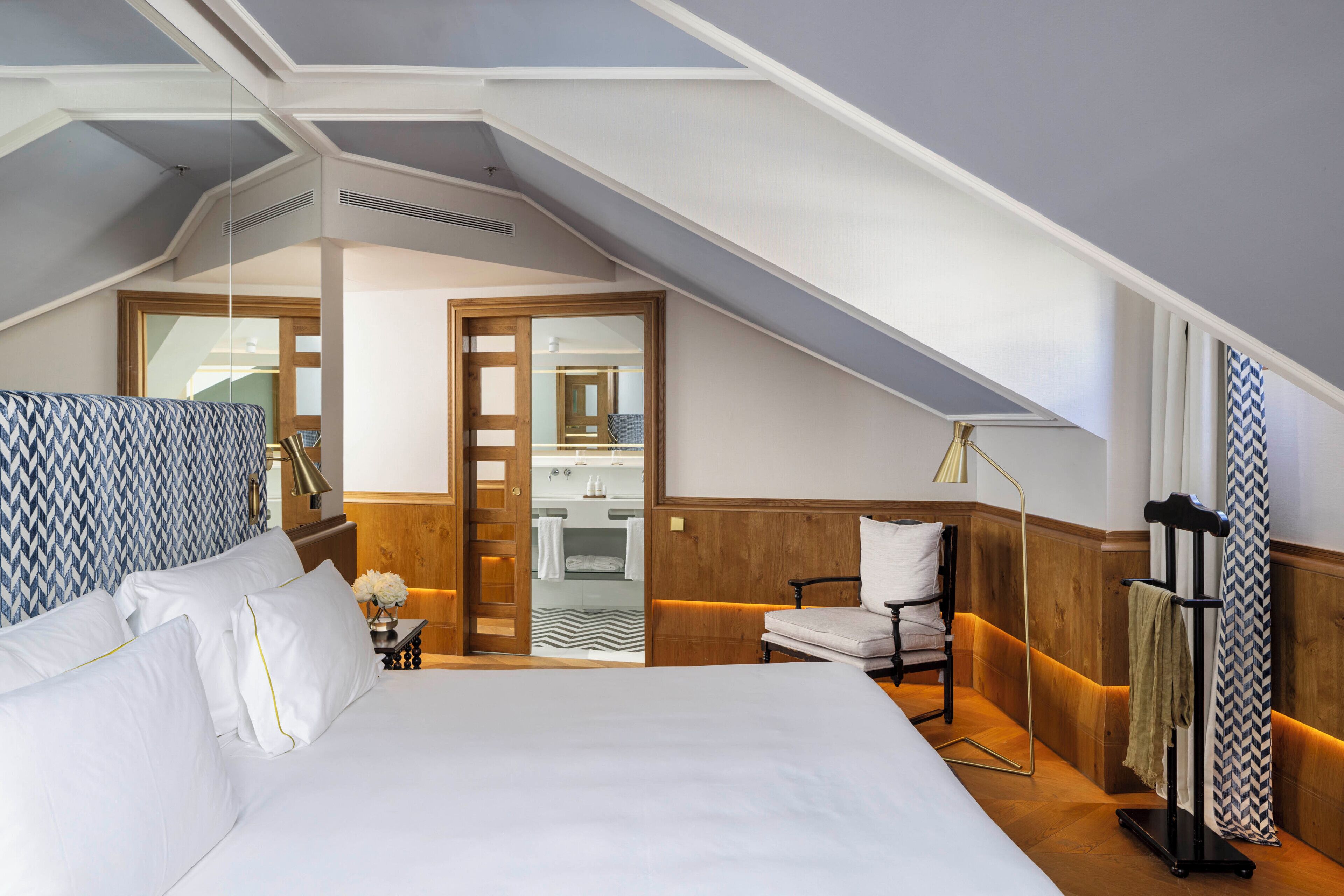 Une chambre d’hôtel avec un grand lit, une armoire en bois, une salle de bain avec un miroir et une vue sur l’extérieur.