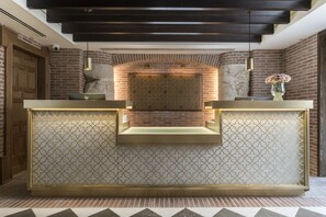 A reception area with a modern design, featuring a patterned wall, a reception desk, and a decorative vase.