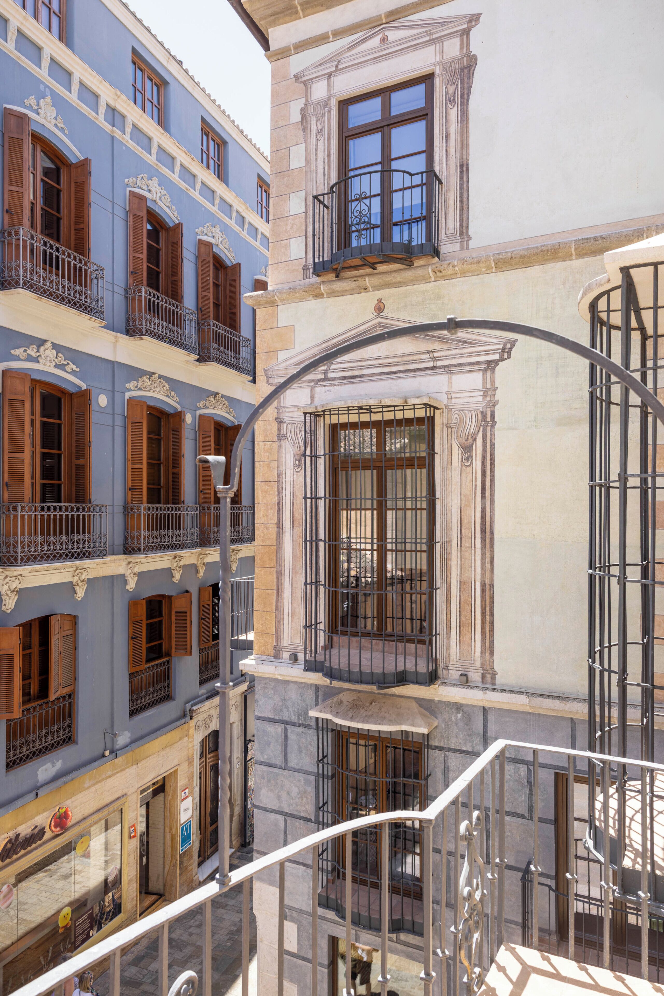 Un edificio de varios pisos con balcones, una escalera y vista a la calle.