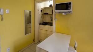 A compact kitchen with a microwave, a phone, and a sink. - Rio Rentals 021 - C005 Studio em Copa (Rio de Janeiro)